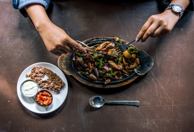 拿着不锈钢勺子和碗盛食物的人